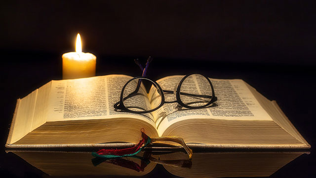 Bible with candle and glasses